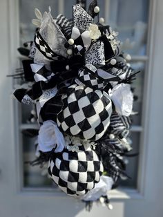 a black and white wreath is hanging on the front door, with ribbons attached to it