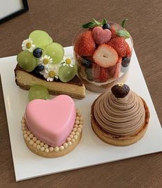 three pastries are arranged on a white plate with fruit and flowers in the background