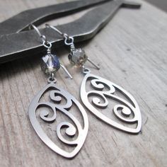 have been having fun with stainless steel earrings lately and here is another pair. These are just under 2.25" in total length and come with a completely hypoallergenic titanium ear wire. I love the scroll design on these stainless steel charms. These are 17x27mm, laser cut, stainless steel. They are wonderful quality and look the same front and back. The top bead could easily be switched out with your color of choice. This particular bead is a 6mm black diamond, renaissance Czech bead with an AB finish. Lots of sparkle. These are perfect everyday earrings for even the most sensitive ears. Modern Hypoallergenic Surgical Steel Jewelry, Everyday Pierced Earrings In Surgical Steel, Everyday Pierced Surgical Steel Earrings, Everyday Surgical Steel Earrings, Modern Teardrop Stainless Steel Earrings, Nickel-free Surgical Steel Plug Earrings For Gift, Nickel-free Metal Plug Earrings As Gift, Nickel-free Minimalist Surgical Steel Earrings, Modern Surgical Steel Jewelry As A Gift