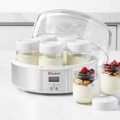 three jars filled with yogurt and fruit on top of a counter next to an electric blender