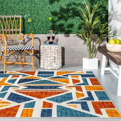 a colorful rug in the middle of a room with two chairs and a potted plant