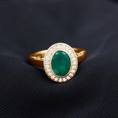 a gold ring with a green stone surrounded by diamonds