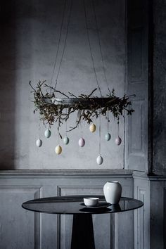 an arrangement of eggs hanging from the ceiling above a table with a bowl on it