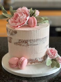 a white cake with pink frosting and flowers on top, sitting on a table