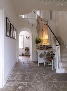 an entry way with stairs and pictures hanging on the wall, next to a white table