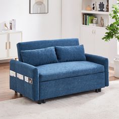 a blue couch sitting on top of a hard wood floor next to a white rug