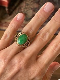 "Sculptural and solid, this antique ring has been expertly hand-fabricated in 14k rose gold. The scrollwork in the mounting is entirely hand chased and beautifully frames the apple green jade cabochon. Currently a ring size 7.5.  Jade: 10.17 x 14.10mm, certified natural and untreated by Mason Kay Weight: 15.7 grams Measurements: 18 mm north to south,  sits just over  1/4\" off of the finger" Antique Green Emerald Ring With Polished Finish, Vintage Jade Cabochon Ring, Antique Oval Cabochon Emerald Ring, Antique Green Signet Ring, Heirloom Jade Ring Jewelry, Vintage Carved Green Ring, Vintage Green Carved Ring, Oval Engraved Green Emerald Ring, Engraved Oval Green Emerald Ring