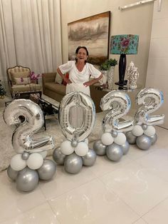 a woman standing in front of balloons that spell out the number twenty