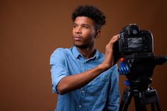 a man is holding up a camera on a tripod and posing for the camera