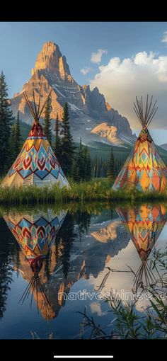 two teepees sitting on top of a lake next to mountains