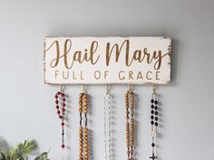 a sign that says hail mary full of grace with beads hanging from it's side