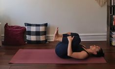 a woman is doing yoga on a mat in front of a bookshelf and pillows