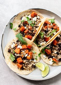 three tacos with black beans, sweet potatoes and cilantro on a plate