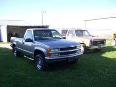 two pickup trucks parked next to each other in the grass