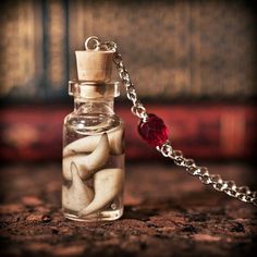 a bottle filled with sand and sea shells sitting on top of a wooden table next to a chain