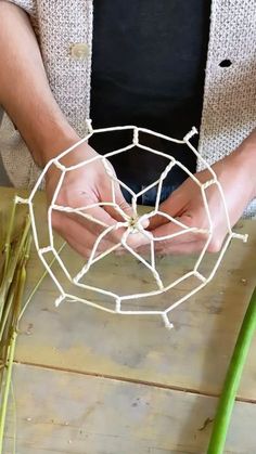 a man is working on some kind of wire art project with his hands and fingers