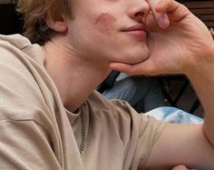 a young man sitting down with his hand under his chin