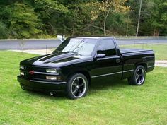 a black truck parked on top of a lush green field