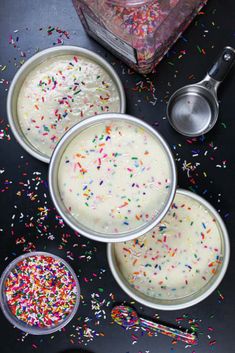 three pans filled with cake batter and sprinkles on top of a table