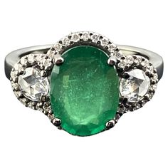 A beautiful 3.01 carat oval cut emerald ring, with 0.30 carats rose cut side stone diamonds and 0.30 carats of full cut diamond halo. The emerald center stone is transparent with a beautiful vivid green color, and all the gemstones are set in solid 18K gold with black rhodium polish, giving the ring an Art Deco look. Currently sized at US7, can be resized. We provide free shipping, and accept returns. Please feel free to message us for more information. Oval Emerald Ring With Single Cut Diamonds, Green Oval Diamond Ring With Single Cut, Green Oval Single Cut Diamond Rings, Oval Emerald Ring With Rose Cut Diamonds, Classic Oval Emerald Ring With Single Cut Diamonds, Oval Emerald Ring With Single Cut Diamonds For Anniversary, Oval Emerald Ring With Rose Cut Diamonds For Anniversary, Anniversary Oval Emerald Ring With Rose Cut Diamonds, Oval Emerald Ring With Diamond Accents