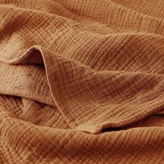 a brown blanket is laying on top of a bed with the sheets pulled back and folded over