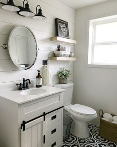 a white bathroom with black and white tile flooring, shelving above the toilet