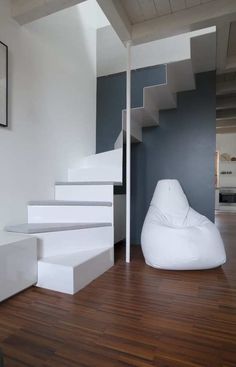 a white chair sitting on top of a hard wood floor next to a stair case