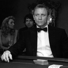 a man in a tuxedo sitting at a table with two other people around him