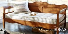 a wooden daybed sitting on top of a hard wood floor next to a window