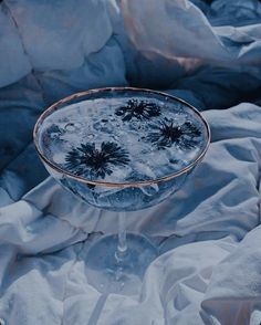 a glass filled with water sitting on top of a bed