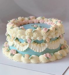 a three layer cake with white frosting and pink flowers on it's sides