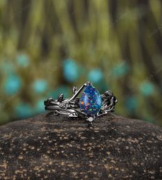 a ring with an opal stone in the middle sits on top of a rock