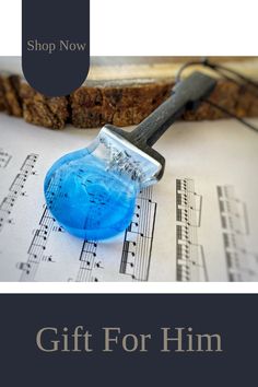 a blue object sitting on top of sheet music with the words gift for him below it