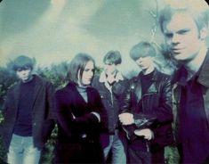 a group of young men standing next to each other in front of a sky filled with clouds