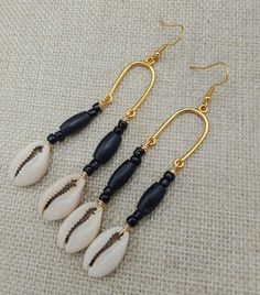 The gold long dangle beaded cowrie earrings are lightweight. The earrings are beaded with wood and glass. The earrings hang approximately 3.25 inches long. If you have any questions please feel free to contact us at anytime. All shipping options are available. All items will be shipped out Monday through Friday. Receipts will be emailed out for immediate access. All items will be shipped out carefully and every shipment can be made with extra insurance upon request. All other concerns and details can be found in our policy section. Our goal is for your 100% satisfaction. If you would like to make a large order please contact us for a coupon code. Our products are not intended for babies or children as we use small pieces, wires and beads. These can be dangerous to them when unsupervised. G Beach Dangle Earrings With Black Beads, Beach Jewelry With Black Dangling Beads, Black Beach Jewelry With Dangling Beads, Black Dangling Beads Jewelry For Beach, Beach Jewelry With Gold And Black Beads, Gold Jewelry With Black Beads For The Beach, Black Beaded Earrings With Dangling Beads For Beach, Gold Dangle Beaded Earrings With Wooden Beads, Gold Dangle Earrings With Wooden Beads