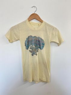 * Era: 70s * Label: None * Size: XXS * Material: Cotton * Condition: good vintage condition! INFO~ *Butter yellow baby tee of your dreams! *Fun, playful, girlhood vibes from this graphic glitter tee! *Faded but still fully legible, this cosmic cutie tee would be a great closet staple! CONDITION~ Flaws noted: good condition with slight discoloration on the back left sleeve + a small white spot on the back as well. Glitter is faded but still brings the sparkle and shine.  SIZING~ Pit to pit: 12" S Vintage Yellow Tops With Screen Print, Retro Yellow Tops With Screen Print, Vintage Yellow Top With Screen Print, Retro Yellow Top With Screen Print, Vintage Yellow Short Sleeve T-shirt, Retro Yellow Tops With Vintage Print, Yellow Vintage Crew Neck Top, Glitter Tee, Graphic Baby Tee