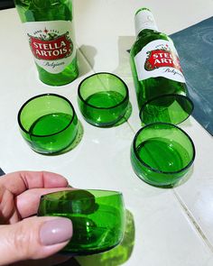 a hand holding a green glass with four glasses in front of it