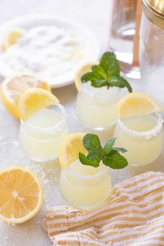 three glasses filled with lemonade and mint garnish on top of a table