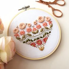 a close up of a embroidery on a table with flowers and scissors next to it