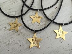 four gold star pendants with the words my shot written on them sitting on a black cord