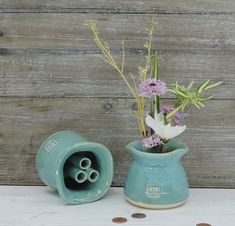 a vase with flowers in it sitting on a table next to some coins and a wooden wall