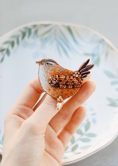 a hand holding a tiny bird on top of a plate