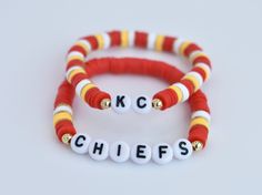 two red and white bracelets with letters that spell kcc chiefs on each one