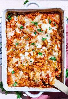 a casserole dish filled with pasta and chicken, garnished with parsley