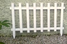 a white fence sitting next to a green plant