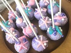 purple cake pops decorated with sea shells and seashells are on a brown plate