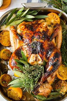 a roasted chicken with herbs and lemons in a pan