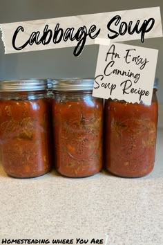 three jars filled with food sitting on top of a counter next to a sign that says cabbage soup