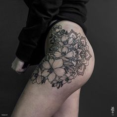 a woman's thigh with flowers and leaves on the side, in black and white