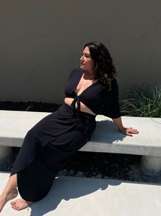 a woman is sitting on a concrete bench